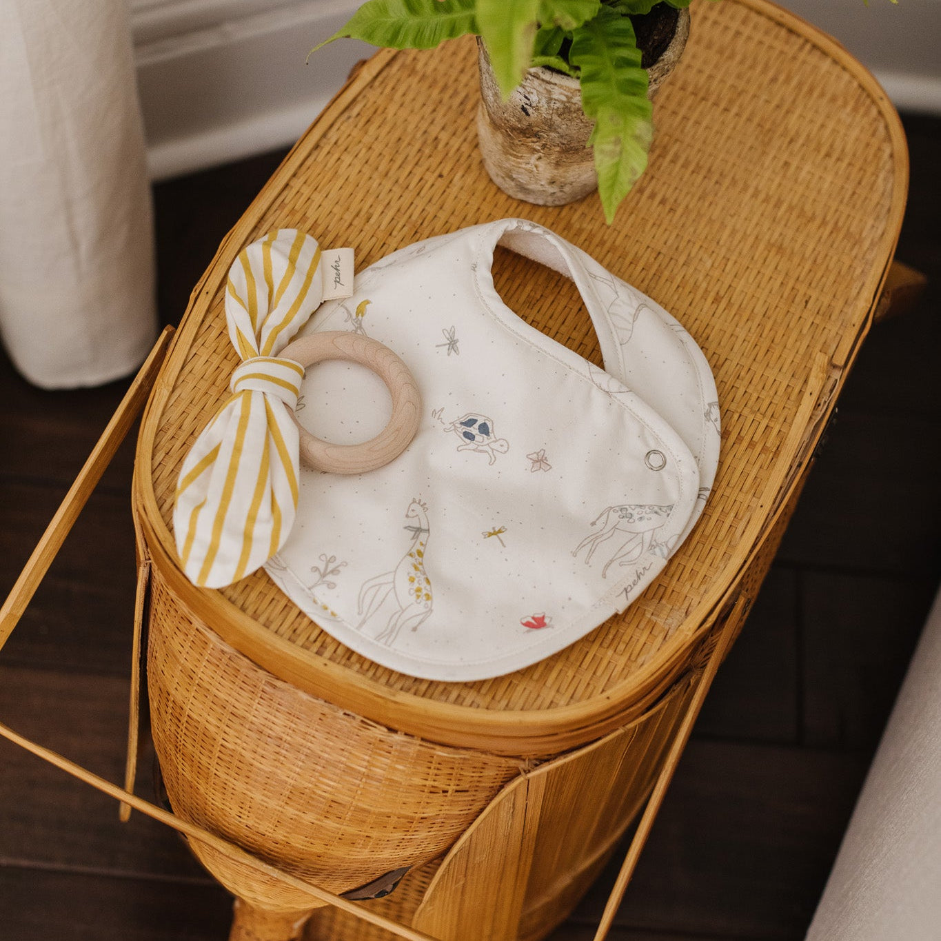 Pehr Bib and Teether laying on rattan basket
