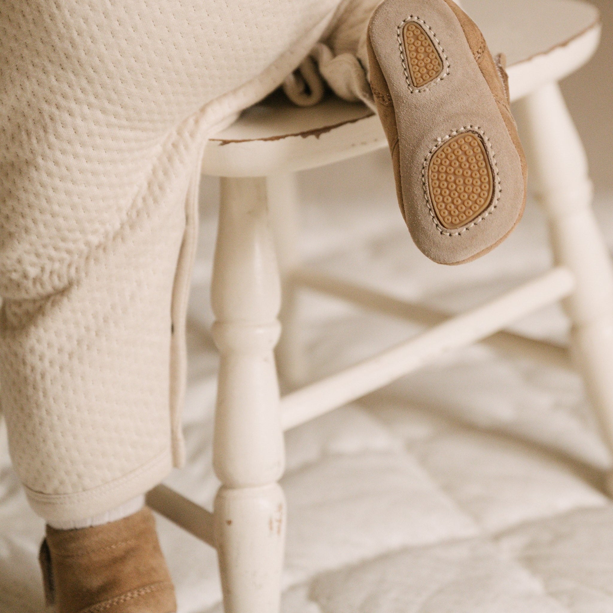 Image of baby trying to climb on a chair wearing Pehr baby booties