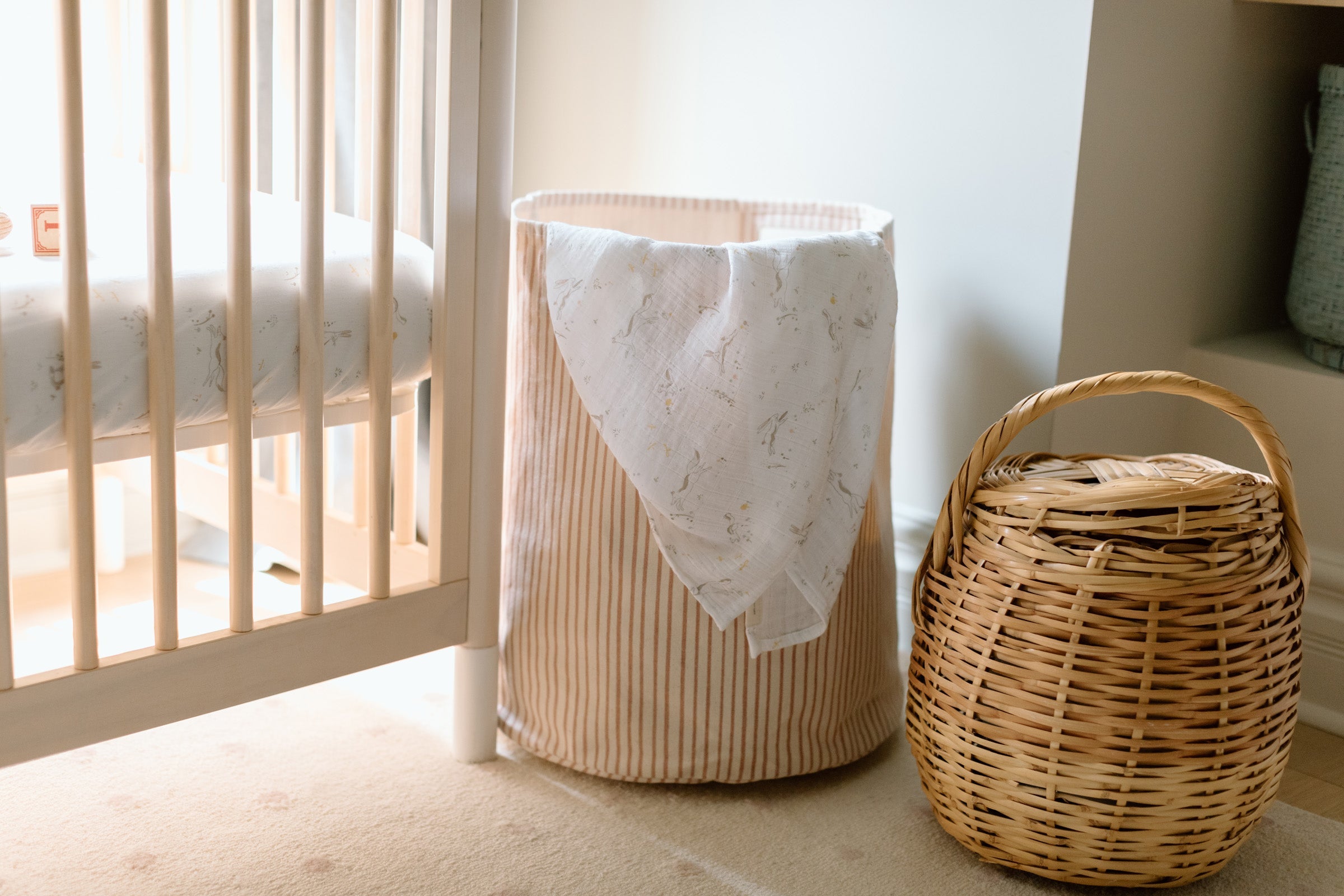 An image of a nursery with a striped hamper and swaddle.